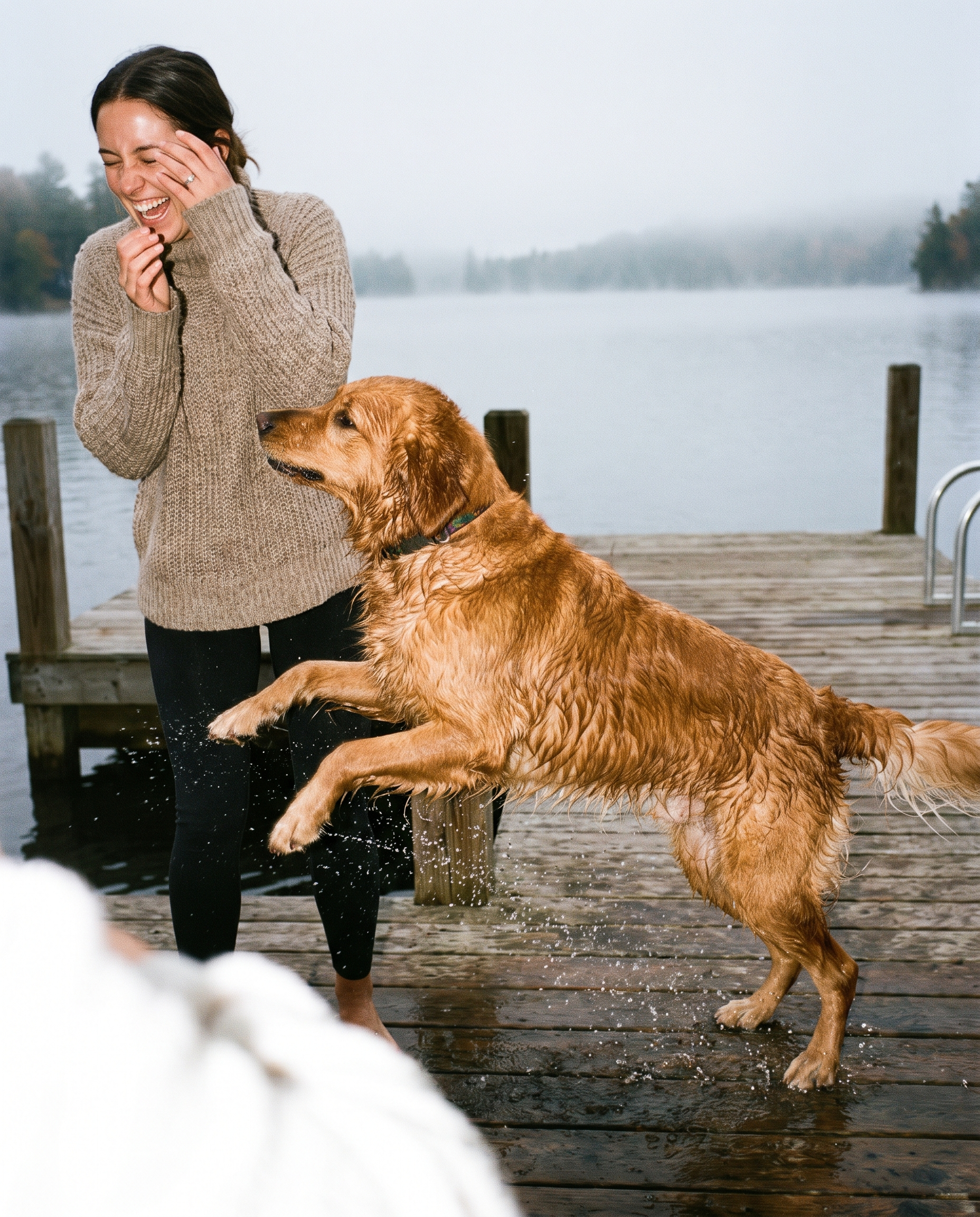 Vrouw lacht met natte hond bij het meer